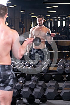 Sexy muscular man doind biceps exercise and looking at the mirror