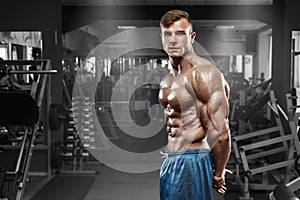 muscular man posing in gym, shaped abdominal, showing triceps. Strong male naked torso abs, working out