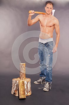 muscular young man chopping fire wood