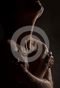 nude female neck and shoulders with water drops on a black background