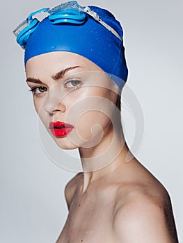 Sexy nude woman in blue swimming cap red lips