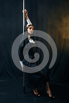 Sexy nun in cassock dances on pole like a stripper