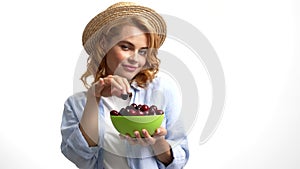 sexy pretty lady in straw summer hat eating sweet cherry berry sensually, seasonal fruit