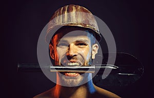Sexy professional builder, engineer or repairman in protective helmet with spade. Closeup portrait angry bearded man in