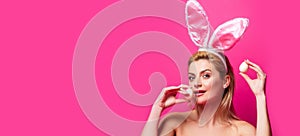 Sexy rabbit woman with eggs, isolated on pink banner, copy space. Wide photo banner for website header design.