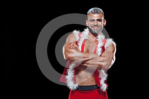 Sexy Santa Claus . Young muscular man wearing Santa Claus hat demonstrate his muscles. Isolated on black background.