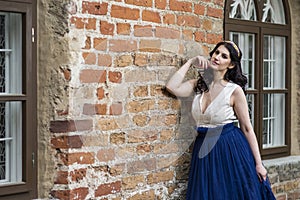 Sexy Sensual Young Brunette Lady Posing in Tiara Against Old Brick Wall Outdoors