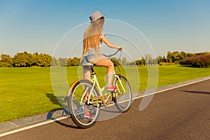Sexy shapely girl with hat and mini shorts ride a bicycle photo