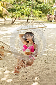 Sexy slim girl enjoys relaxing in a hammock on the shore of a tropical paradise island