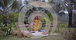 Sexy slim model posing to the camera, she seats on the chair during picnic