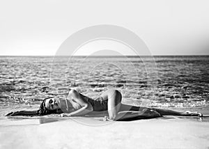 Sexy slim woman girl is lying on the beach sand on th background of the sea during vacation on seashore. Black and white