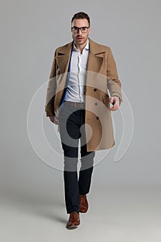 Sexy smartcasual guy wearing long coat and walking