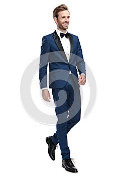 Sexy smiling man in blue tuxedo walking