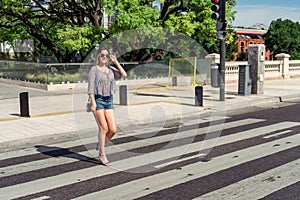 A sexy smiling young woman crossing an avenue on the pedestrian or zebra path