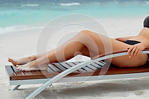 Sexy Suntan Bikin Woman Legs Relaxing Lying Down near Beach In Resort Spa Hotel On Travel Holidays Vacation. Beauty Skincare