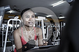 and sweaty Asian woman training hard at gym using elliptical pedaling machine gear in intense workout photo