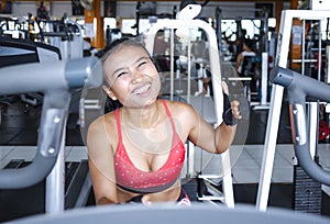 and sweaty Asian woman training hard at gym using elliptical pedaling machine gear in intense workout photo