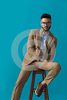 Sexy unshaved businessman with glasses holding arms in fashion pose