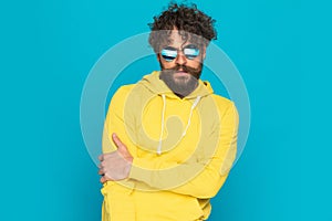 Sexy unshaved guy in yellow shirt holding elbow in a fashion pose