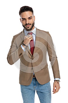 Sexy unshaved man being happy and adjusting red tie