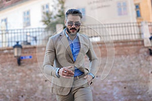 sexy unshaved man with sunglasses walking with hand in pocket