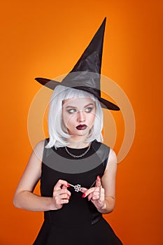 Sexy witch with dark lips and white hair looking away on orange studio background.