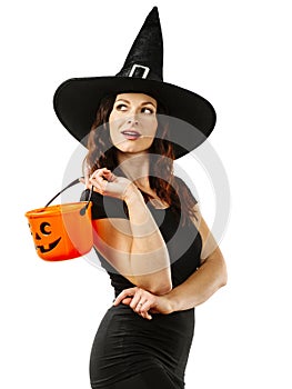 Sexy witch smiling and holding Halloween pumpkin bucket