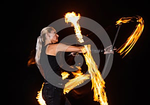 sexy woman artist twirl burning batons during fire performance at night, celebration