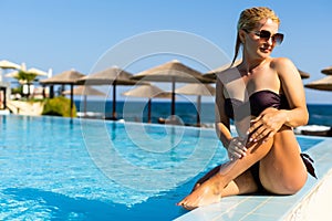 Sexy woman in bikini is posing in the swimming pool. Wellness and spa luxury resort.
