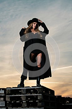 Sexy woman in black fashion coat, hat and black shoes boots. Beautiful young woman wearing fashionable spring clothes