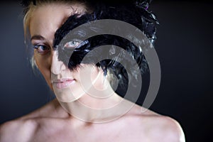 woman with black feather half mask