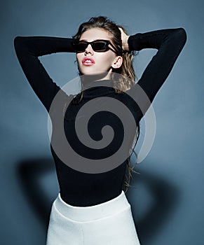Sexy woman in black sunglasses. Portrait of sensual girl looking away isolated on gray.