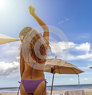 Sexy woman dancing and enjoying the party under the rays of the sun on a white and golden sand beach with the Caribbean Sea.