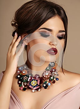 woman with dark hair and bright makeup, with necklace