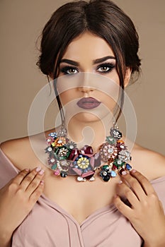 woman with dark hair and bright makeup, with necklace