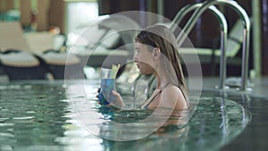 Sexy woman enjoying cocktail at luxury pool. Woman sipping alcohol