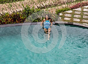 woman enjoying the sun at infinity summer swimming pool at luxurious resort