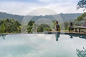 woman enjoying the sun at infinity summer swimming pool at luxurious resort