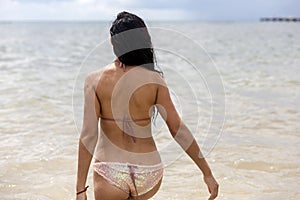 Sexy woman entering the crystal clear and warm water of a white sandy Caribbean beach in the Caribbean Sea in the Mayan Riviera.