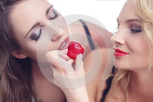 woman feeding lesbian lover with strawberry photo