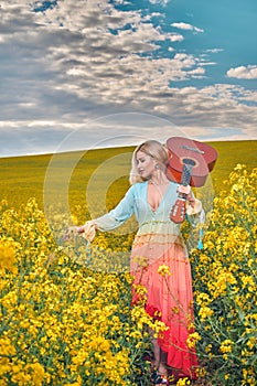 sexy woman in the field with a guitar. concept freedom, inspiration, relaxation