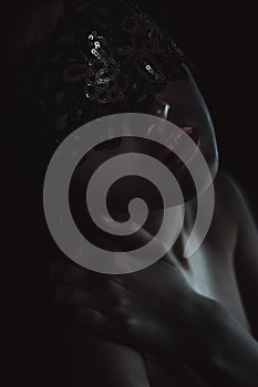 woman with finger on her red lips showing shush. Erotic girl with lace mask over black background. Black and white