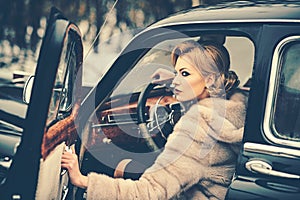 Sexy woman in fur coat. Call girl in vintage car. Travel and business trip or hitch hiking. Retro collection car and