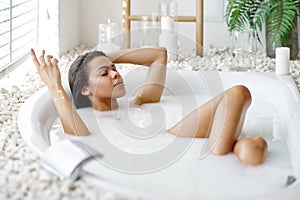 Sexy woman with glass in bath with milk