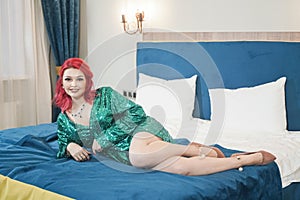 Sexy woman in green stylish sparkling glitter dress ready for christmas party and relaz by waiting in her bed alone photo