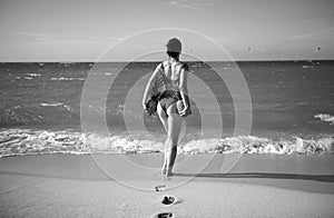 Sexy woman holding fresh pineapple. Buttocks of girl in bikini with fruit pineapple on beach background, summer vacation