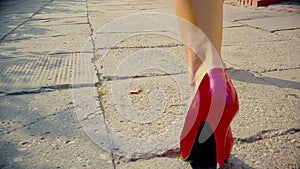 Sexy woman legs in red high heels shoes walking in the city urban street. Steadicam Stabilized shot.  Female legs in high-heeled