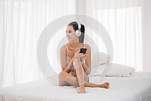 Sexy woman listening to musics from smartphone in bedroom photo