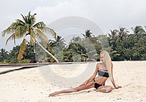 woman with long blond hair in elegant black bikini posing a