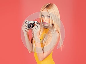 Sexy woman photographer hold camera isolated on pink.